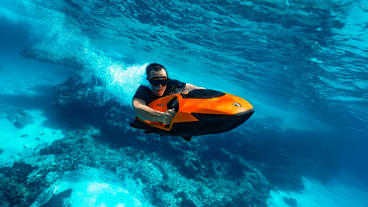 Diver riding the SEABOB SE63 underwater over a coral reef
